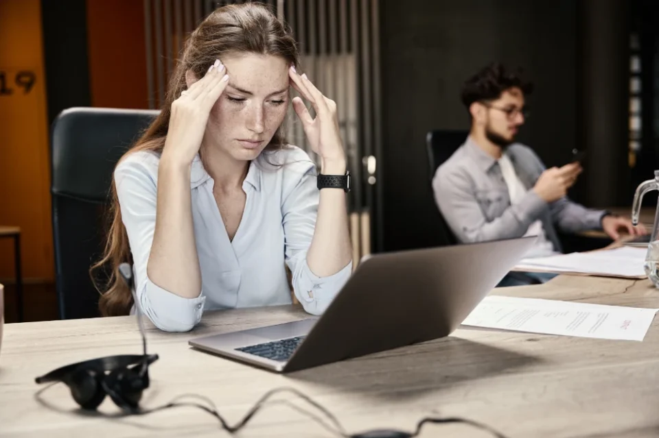 Stressed employee resting her head in her hands at a workplace desk