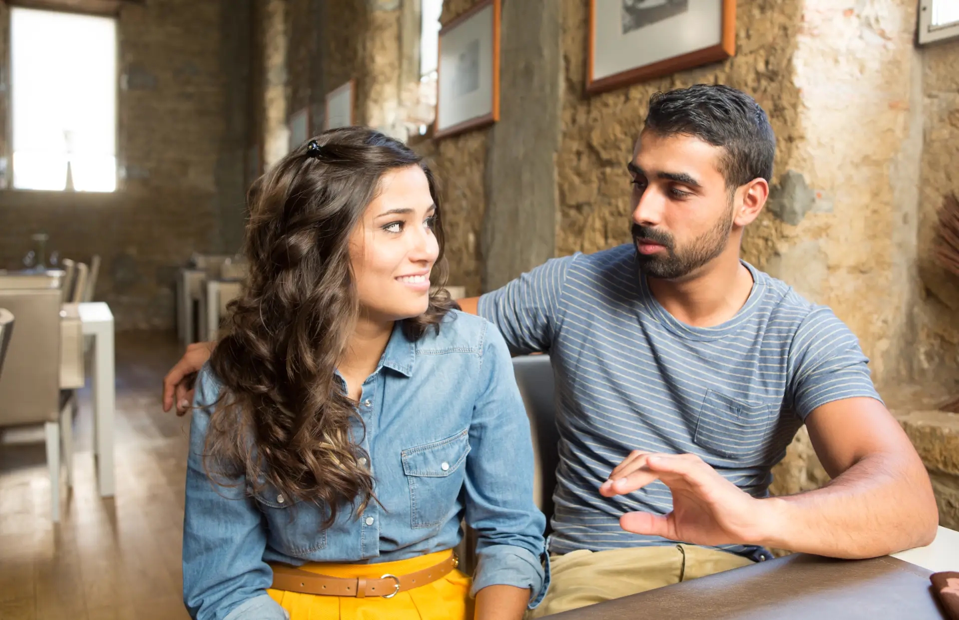 Young couple sitting close together at a cafe, having a warm, attentive conversation