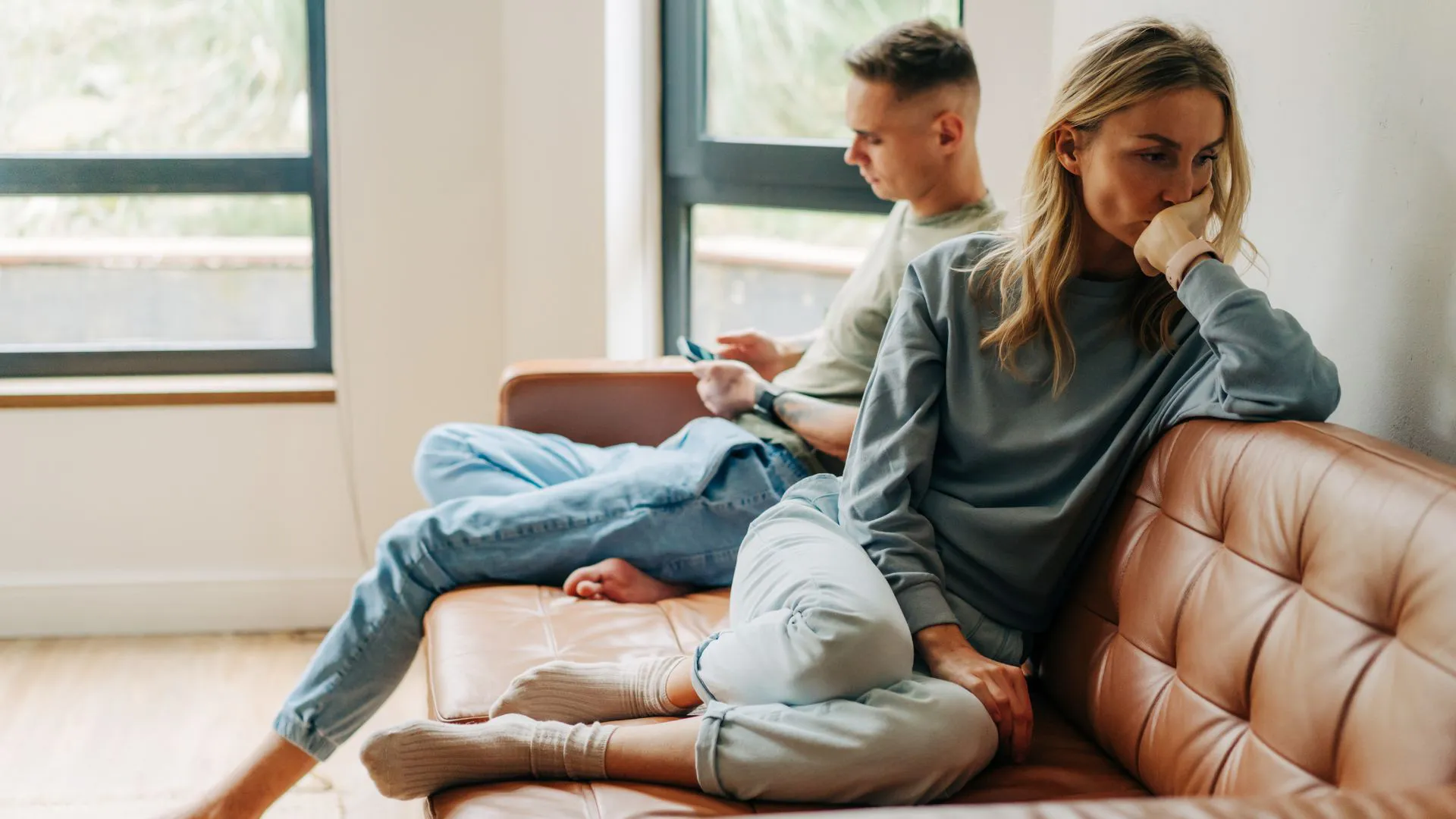 Couple sitting apart on a couch looking upset and disconnected